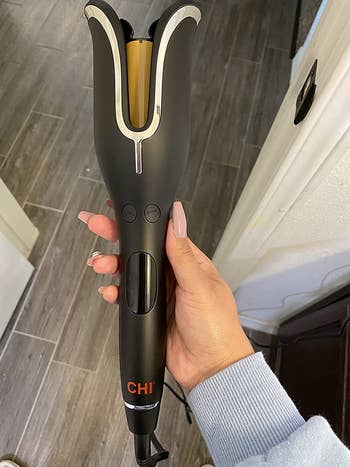 A reviewer holding their Chi curling tool