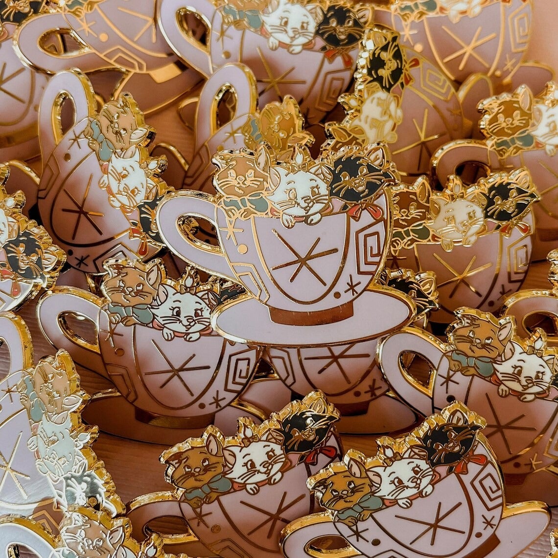 an enamel pin of the three aristocat kittens in a teacup
