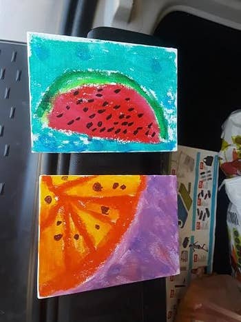 Two tiny canvas paintings picture a watermelon portion and an orangish slice, with stylized seeds, suitable for location decoration