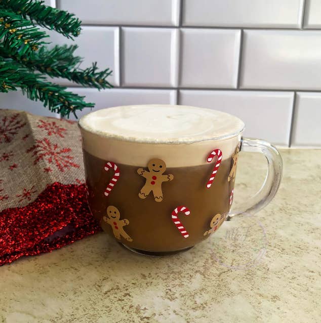 a glass coffee mug with decals of candy canes and gingerbread men on it
