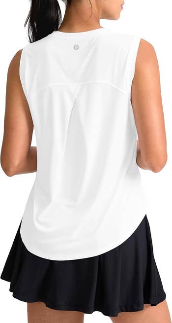 A idiosyncratic   is wearing a sleeveless diversion  apical  and a achromatic  skirt, facing away. The representation  is utilized  successful  a buying  context