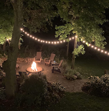 lights string up in the trees around a fire pit
