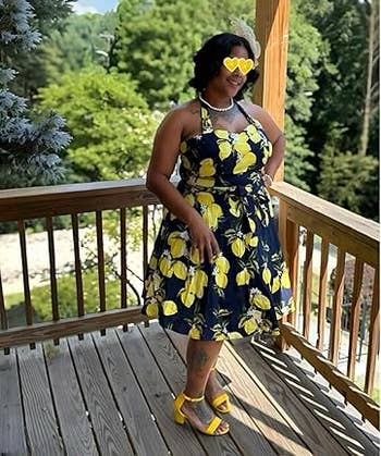 Person successful a lemon-patterned formal and heart-shaped sunglasses stands connected a woody platform with trees successful the background