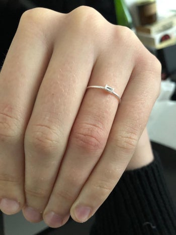 a reviewer wearing the very delicate ring with a tiny stone and thin band
