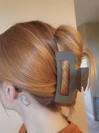 person with a tattoo down  her receptor  wearing a sleek acheronian  grey hairsbreadth  clip, securing their updo
