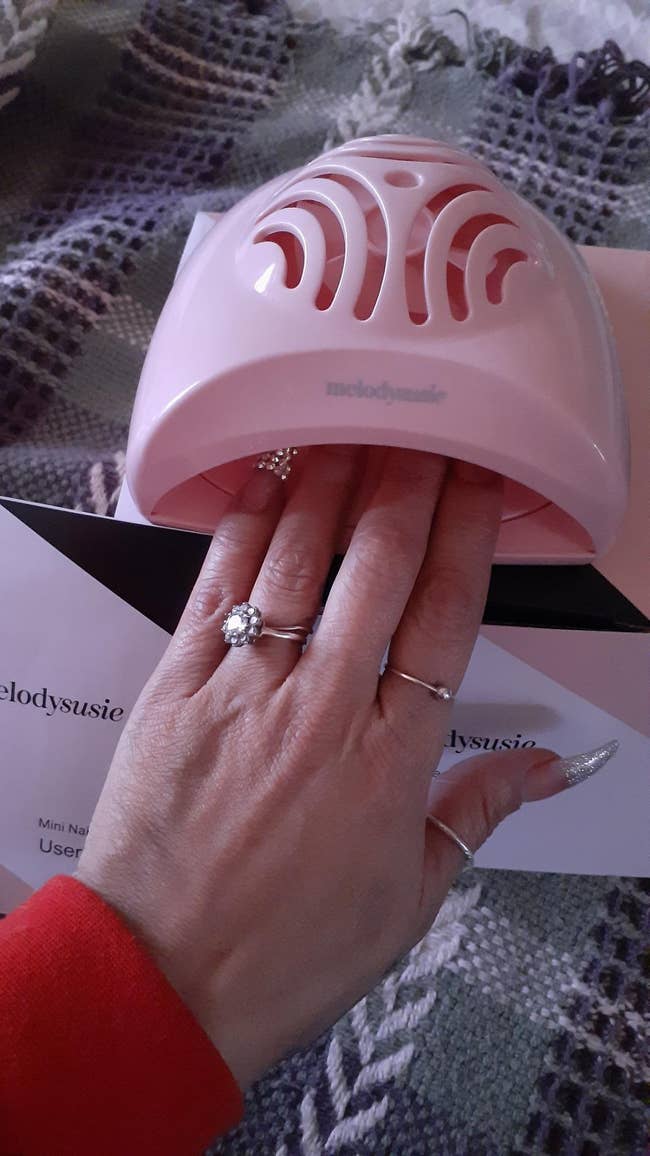 reviewer with hand inside pink nail dryer