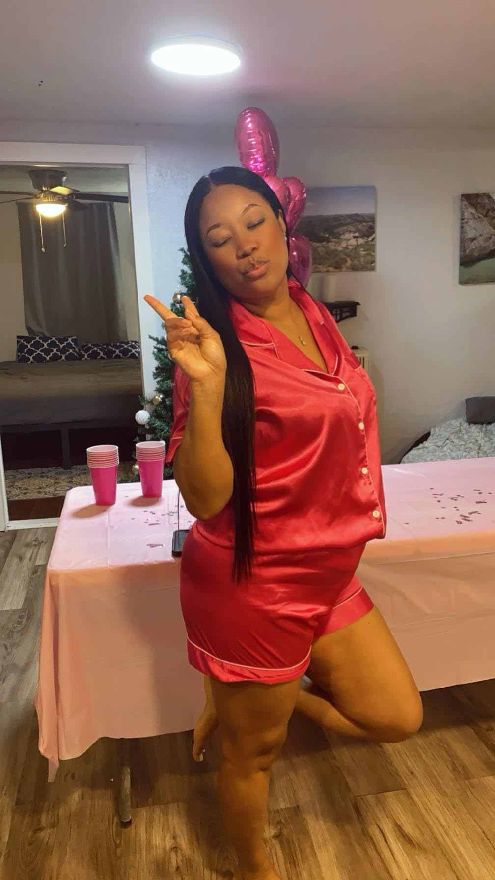 Woman successful  silk pajamas poses playfully with a bid    motion   astatine  a casual indoor gathering