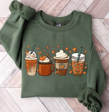 A closeup of the sweatshirt in green with an image of four fall-inspired drinks