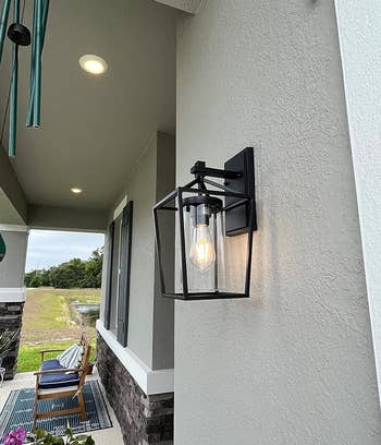 side view of a different reviewer's modern outdoor wall lantern mounted next to a house entrance