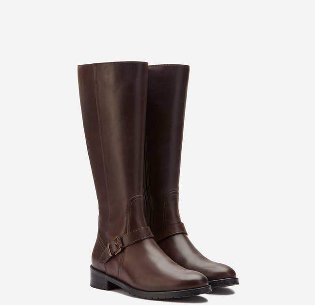 The brown leather knee-high boots with a buckle on the side near the ankle