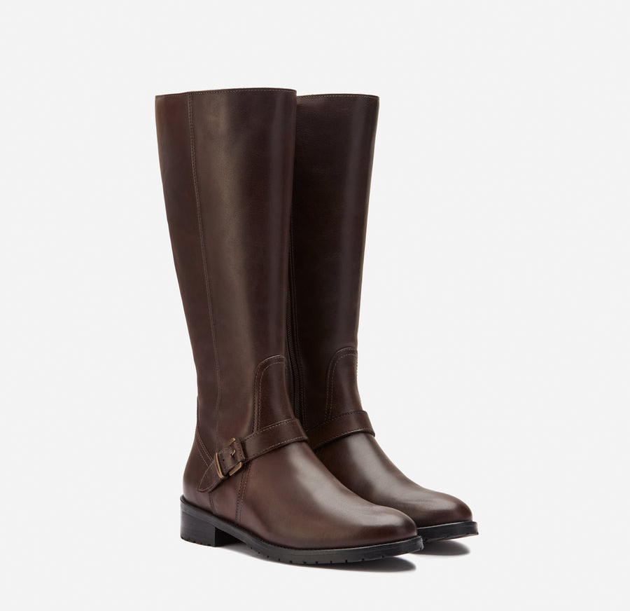 The brown leather knee-high boots with a buckle on the side near the ankle