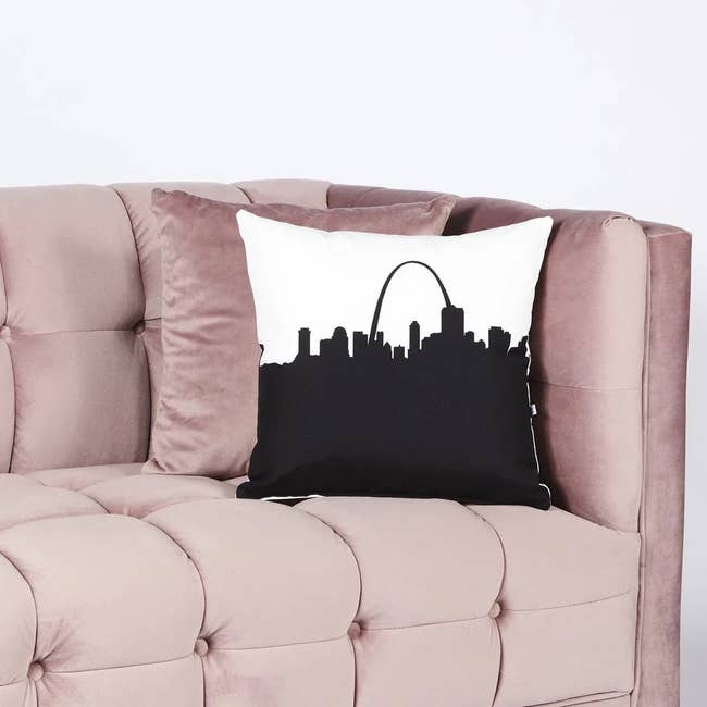 A decorative pillow with a city skyline design on a couch
