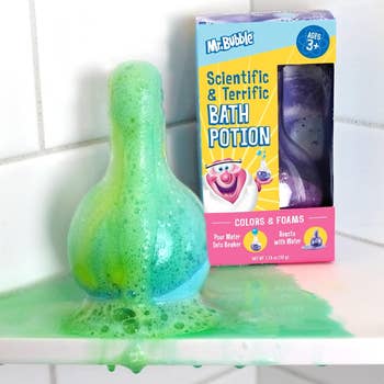 a beaker with green and blue foam overflowing from it