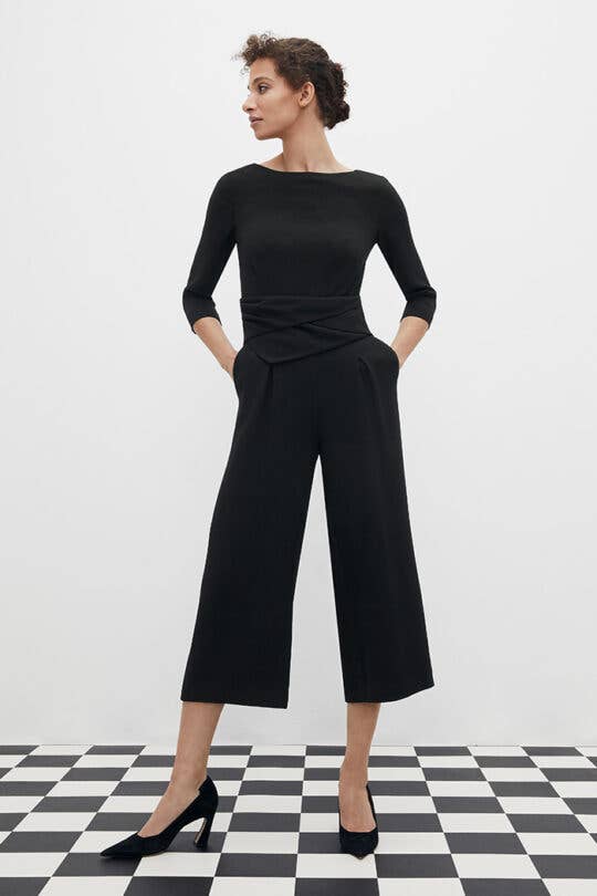 a model in a cropped black jump suit