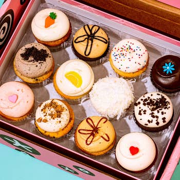 a dozen cupcakes in various flavors in a box 