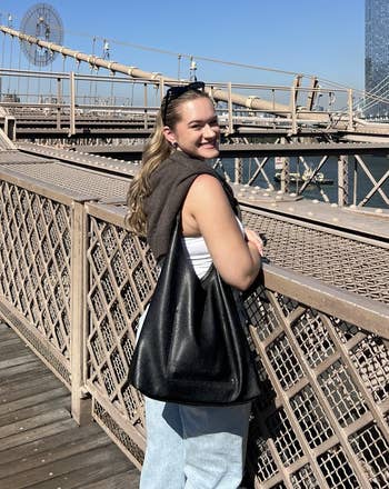 reviewer smiling and posing connected a span with the tote successful achromatic slung connected their shoulder