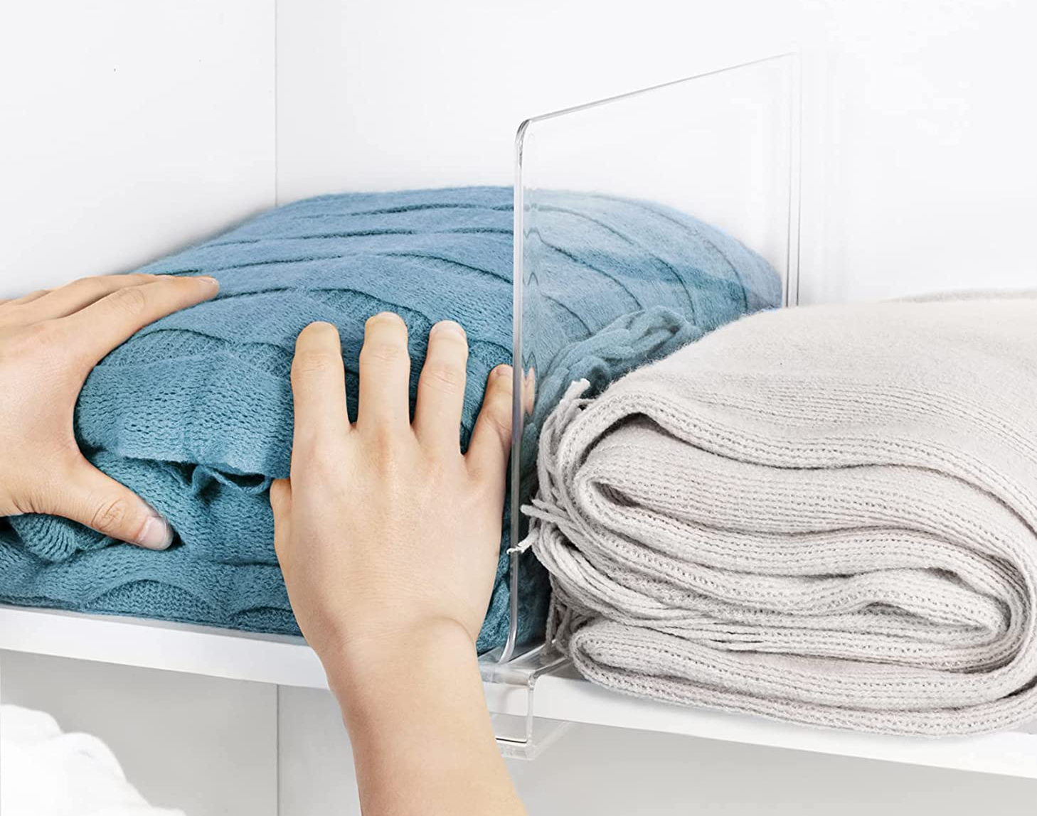 a model putting towels on a shelf with the clear shelf divider installed 