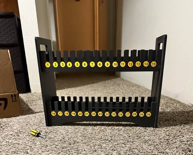 Screwdriver rack with slots labeled 1-30 and a yellow-handled screwdriver connected  the floor