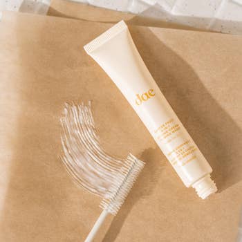 Doe citrus lip gloss tube with applicator showing texture on a neutral background