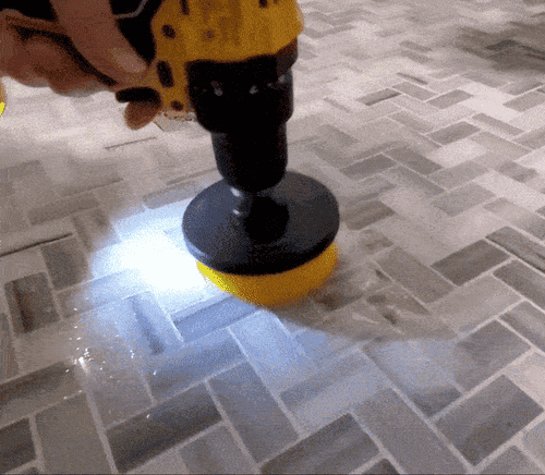 A gif of a reviewer using one of the brush attachments to clean their bathroom tile floor