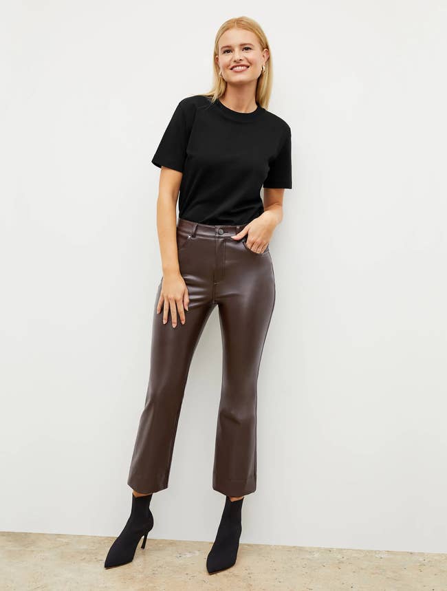 a model wearing brown vegan leather ankle pants with a black tee and black booties