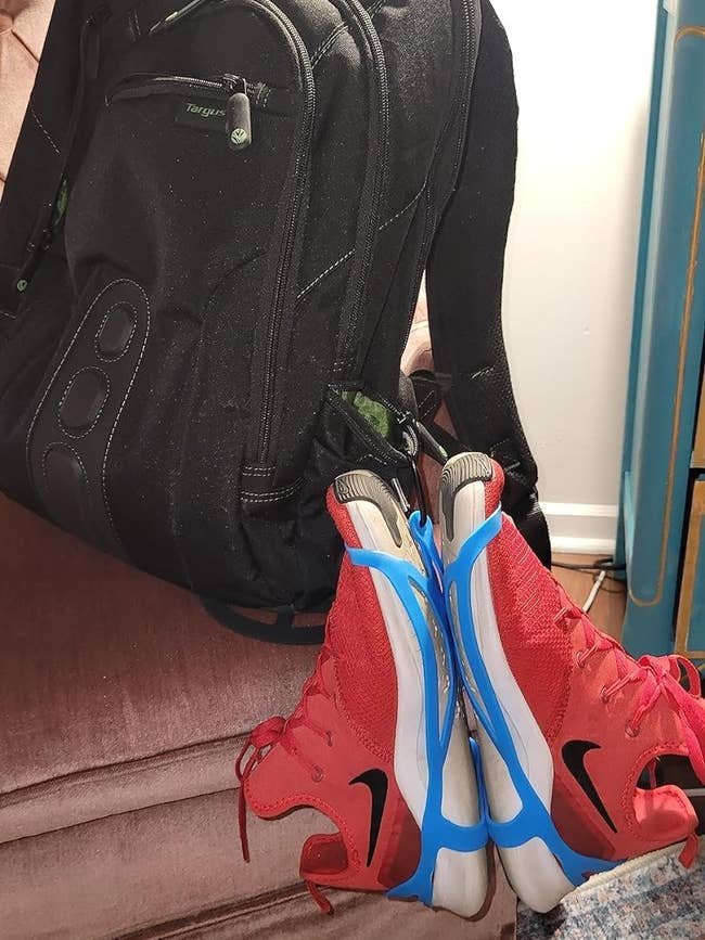 Backpack with a pair of red sneakers hanging from it with the shoe holsters