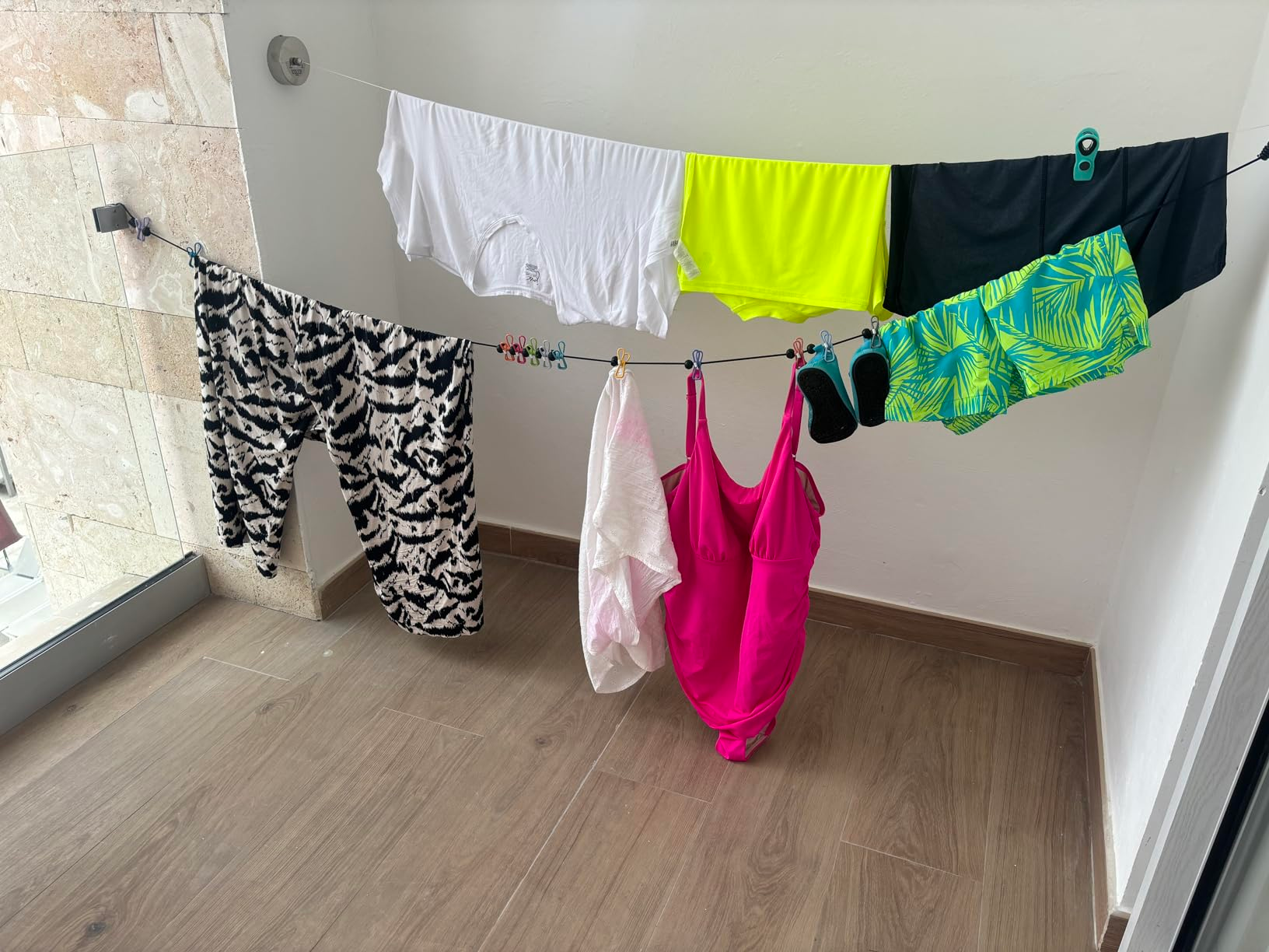 Wet swimwear hanging from the clothesline set up in a hotel restroom