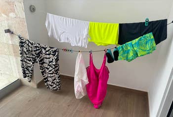 Wet swimwear hanging from the clothesline set up in a hotel restroom