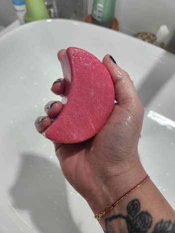 Hand holding a moon-shaped shampoo bar