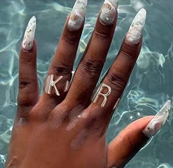 model's hand wearing the silver K and R initial rings