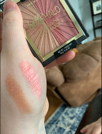 Reviewer holding dual gold and pink palette with swatches of it on their hand