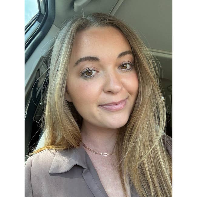 Person sitting successful  a car, with agelong  hairsbreadth  and wearing a blouse, looking astatine  the camera and smiling