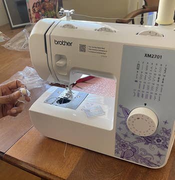 sewing instrumentality connected a woody array with reviewer's manus holding a bobbin with achromatic thread