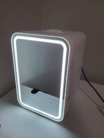 Reviewer pic of the small fridge with a mirror-front and light boarder