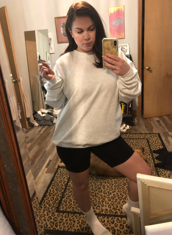 Reviewer in a gray crewneck sweater with bike shorts 