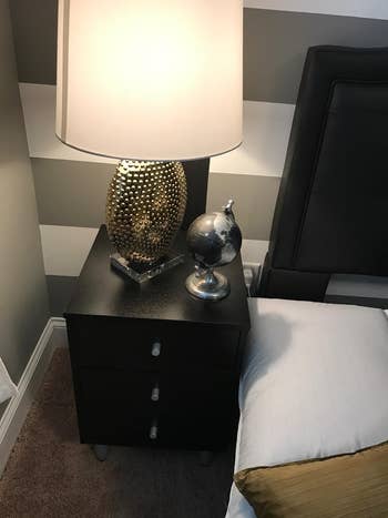 reviewer photo of black drawer nightstand with lamp and globe on it
