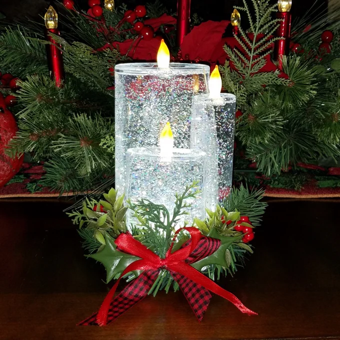 Reviewer image of three clear glittery flameless candles turned on sitting inside wreath with red bow