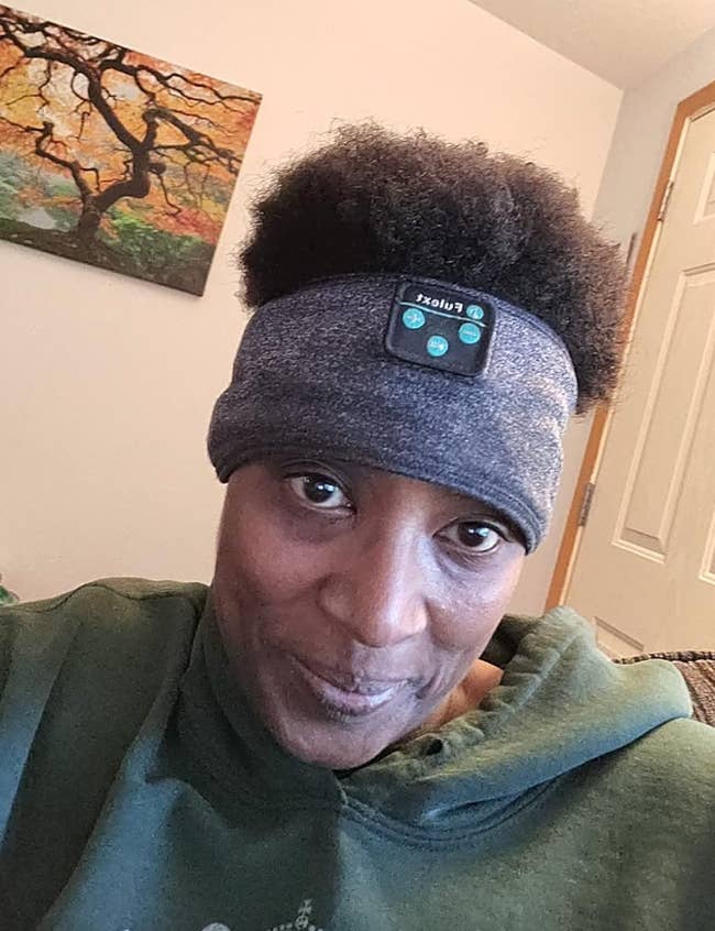 A idiosyncratic wearing a greenish hoodie and a headband with a tiny instrumentality attached, sitting indoors with a coating connected the partition down them