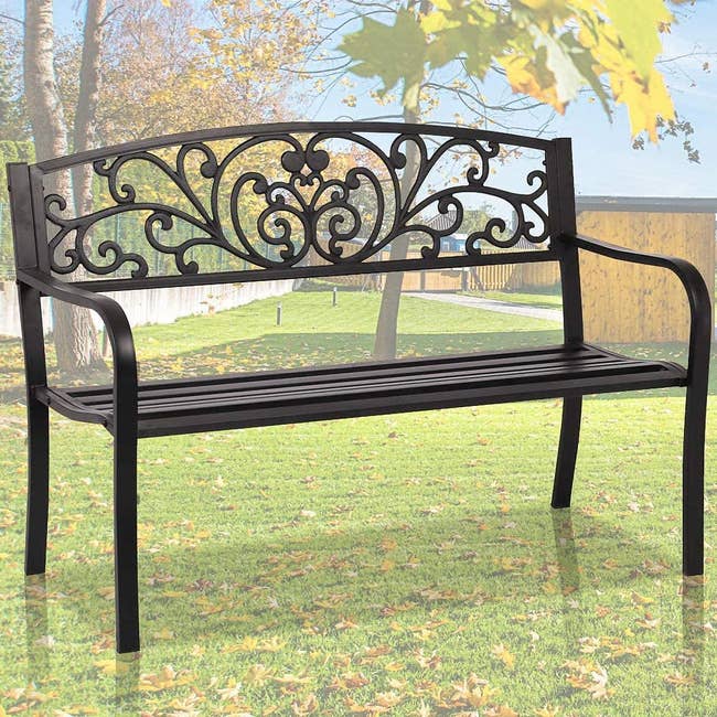 Black wrought iron bench outside on grass