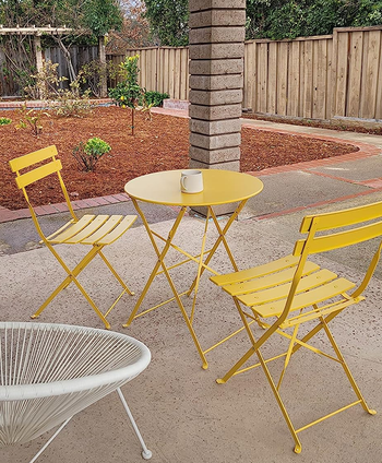 reviewer photo of the yellow bistro set on a patio