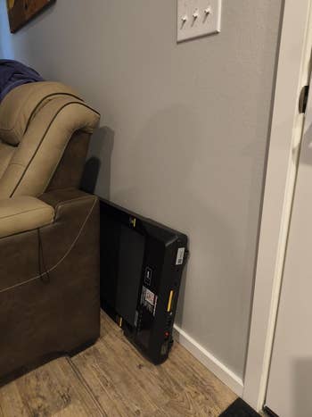 Compact treadmill leaning against a partition  beside a sofa  successful  a surviving  room, emphasizing unused electronics