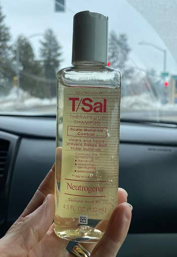 Hand holding Neutrogena T/Sal Shampoo bottle