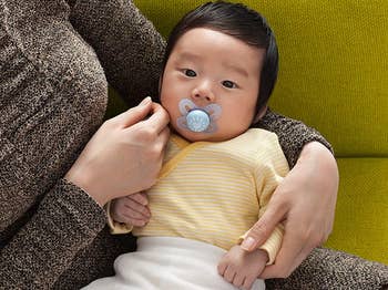 a baby sucking on a blue pacifier