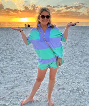 Person smiling connected a formation astatine sunset, wearing a escaped striped outfit. Hands are raised, and sunglasses are worn. Two radical beryllium by the water