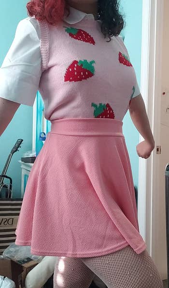 another reviewer in a strawberry-patterned knit top and pink skirt with white fishnet tights