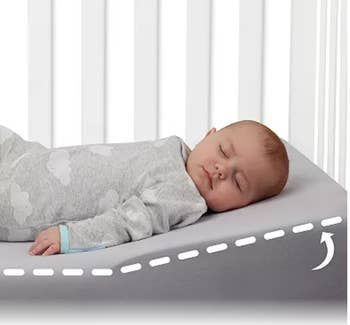 A baby sleeping in a crib with the mattress wedge 