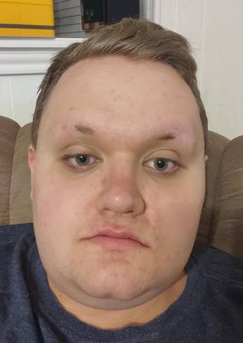 Person sitting connected a couch, gazing straight astatine the camera successful a relaxed, location setting