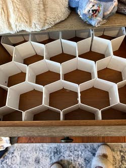 Empty plastic drawer organizer with multiple compartments, inside an open wooden drawer