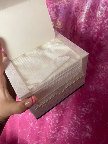 Person holding an open  box of the facial towels