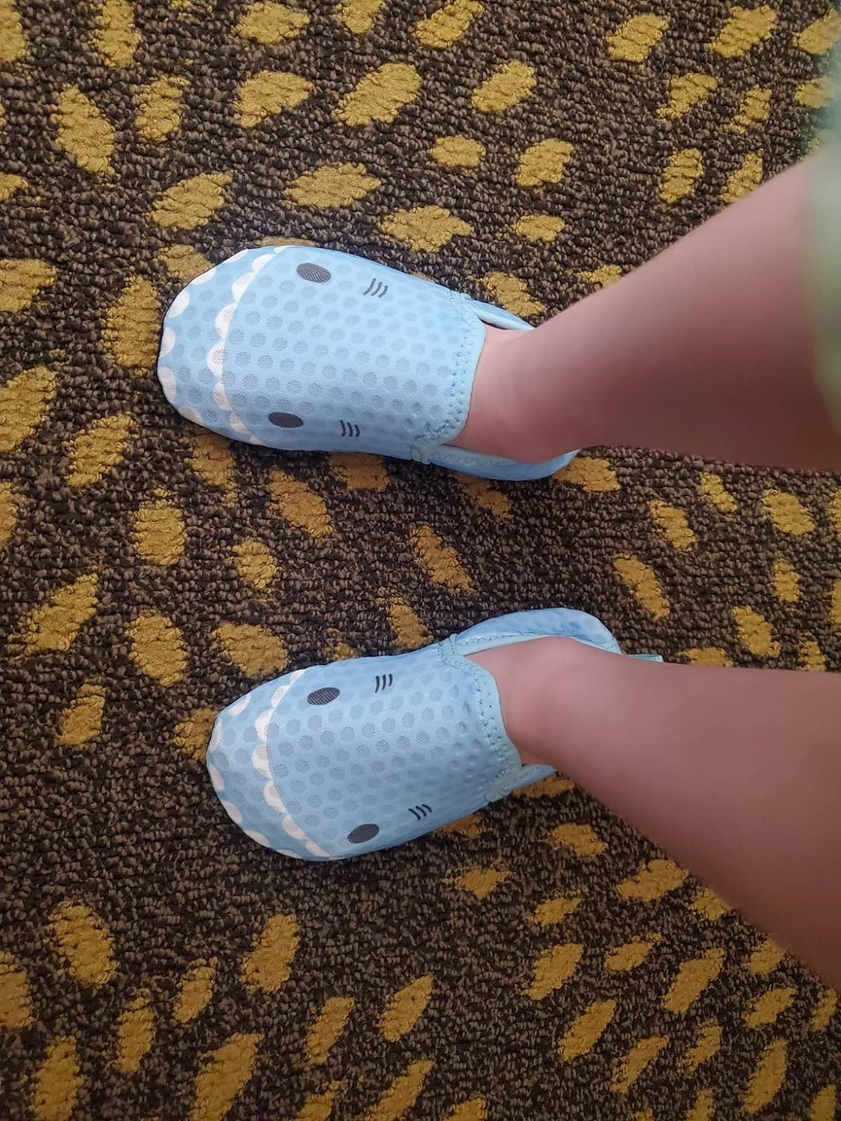 reviewer's child wearing blue slippers with cartoon shark faces